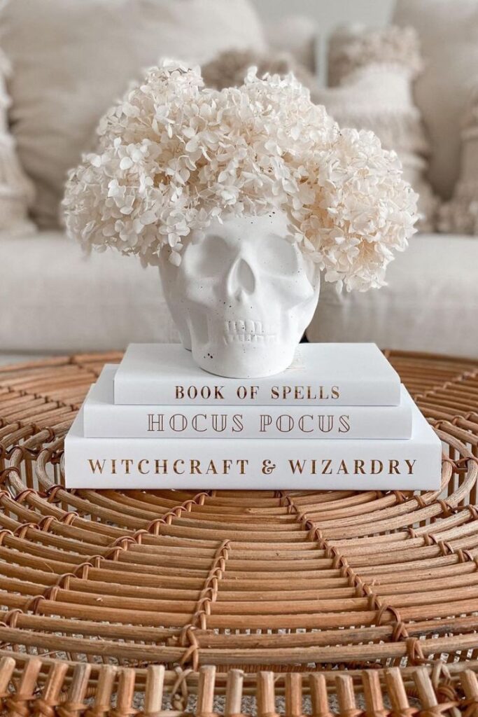 all white DIY Halloween decor using a skull vase, flowers, and books